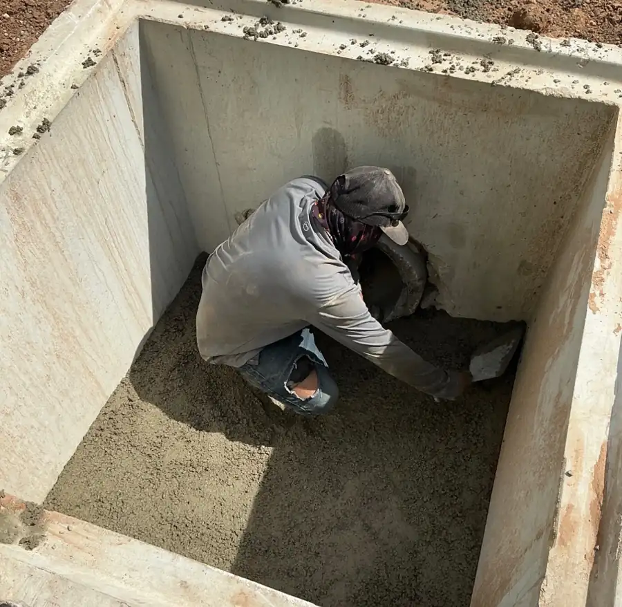 Worker grouting around a pipe penetration inside a precast concrete vault